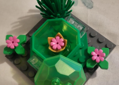 Photograph of a Lego Serious Play student project with green blocks and pink flowers.